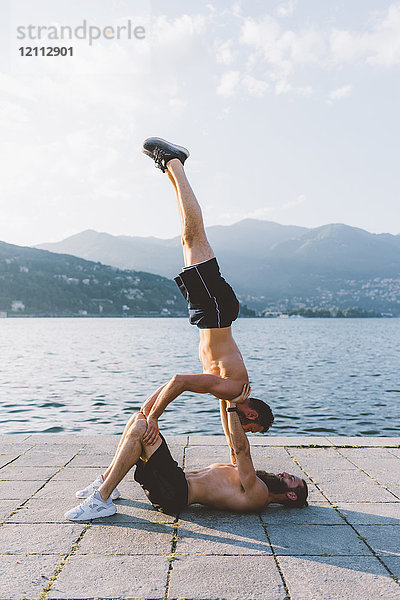 Zwei junge Männer machen Team-Handstand am Wasser  Comer See  Lombardei  Italien