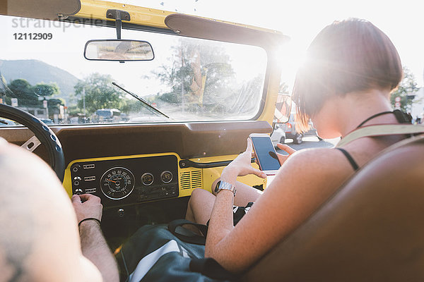 Junge Frau betrachtet Smartphone im Geländewagen  Como  Lombardei  Italien