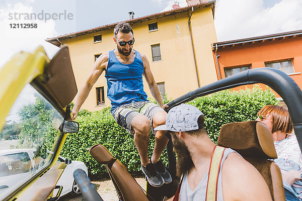 Junger Mann auf Autoreise springt in Geländewagen  Como  Lombardei  Italien