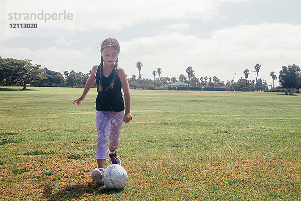 Schulmädchen kickt Fussball auf Schulsportplatz