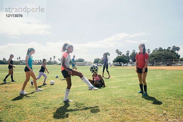 Schulmädchen üben auf dem Schulsportplatz mit dem Fussball