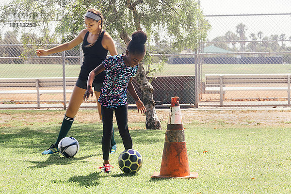 Schulmädchen üben dribbelnden Fussball auf dem Schulsportplatz