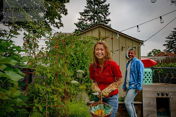 Porträt eines reifen Gartenpaares mit frisch gepflückten Tomaten im Korb