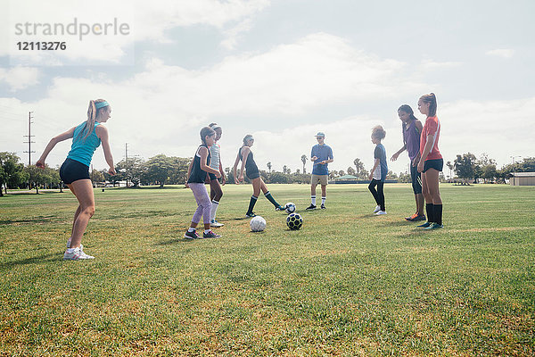 Schulmädchen treten sich auf dem Schulsportplatz Auge in Auge einen Fussball zu