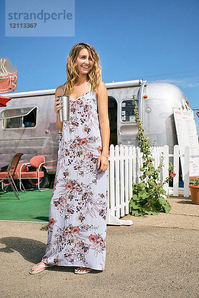 Junge Frau im Maxi-Kleid am Airstream-Café