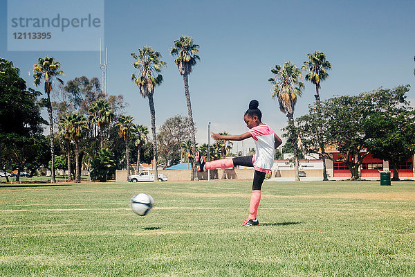 Schulmädchen kickt Fussball auf Schulsportplatz
