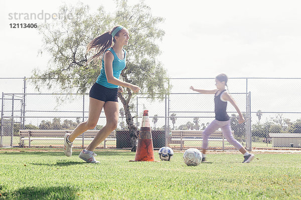 Schulmädchen üben dribbelnden Fussball auf dem Schulsportplatz