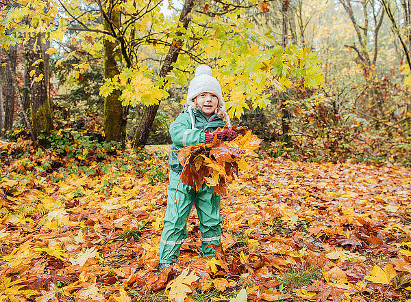 Mädchen spielt mit Herbstblättern