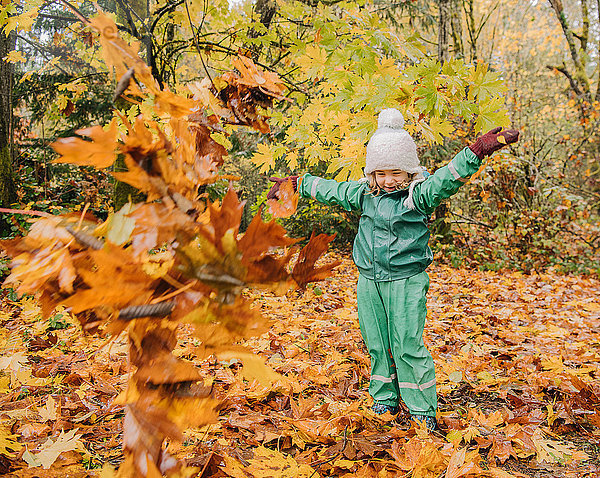 Mädchen spielt mit Herbstblättern