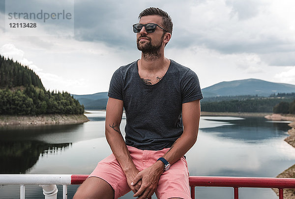 Mann sitzt auf Sicherheitsbarriere am See  Koralat  Zagrebacka  Kroatien