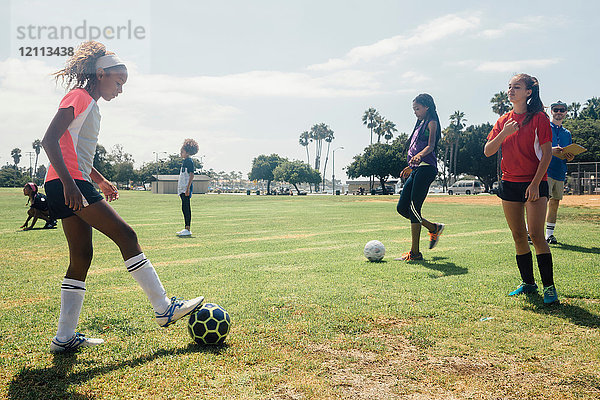 Schulmädchen beim Üben von Angesicht zu Angesicht mit einem Fussball auf dem Schulsportplatz