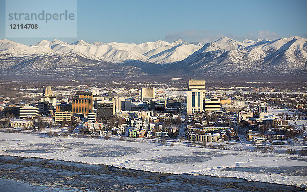 Luftaufnahme der schneebedeckten Innenstadt von Anchorage und der Chugach Mountains in der Ferne  Cook Inlet im Vordergrund  Süd-Zentral-Alaska im Winter; Anchorage  Alaska  Vereinigte Staaten von Amerika