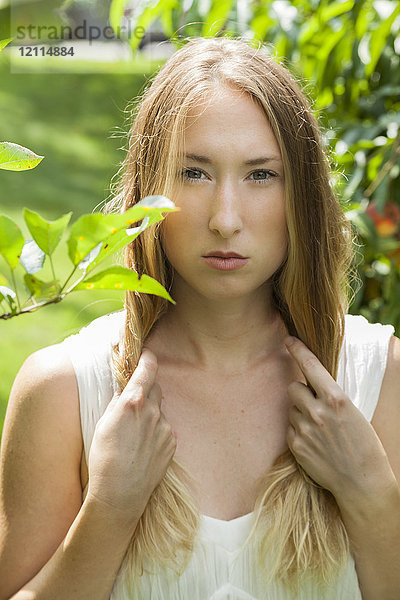 Schöne junge Frau mit langem blondem Haar in grünem Laub stehend; Connecticut  Vereinigte Staaten von Amerika
