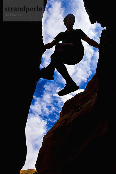 Blick nach oben auf die Silhouette eines Kletterers in einem Slot Canyon in der Wüste; Hanksville  Utah  Vereinigte Staaten von Amerika