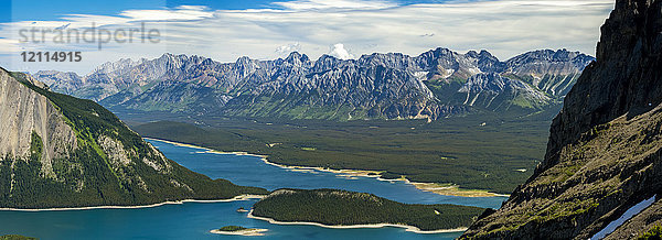 Panorama auf dem Gipfel eines Bergrückens mit Blick auf einen farbenfrohen Alpensee und eine Bergkette in der Ferne mit blauem Himmel und Wolken; Kananaskis Country  Alberta  Kanada