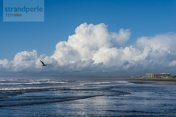 Der Pazifische Ozean spült über den Strand  während sich Wolken über der Küstenstadt Seaside abzeichnen; Seaside  Oregon  Vereinigte Staaten von Amerika