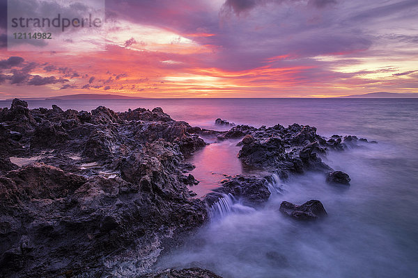 Dramatischer Sonnenuntergang über dem Meer mit Wasserfällen entlang der zerklüfteten Küstenlinie; Wailea  Maui  Hawaii  Vereinigte Staaten von Amerika