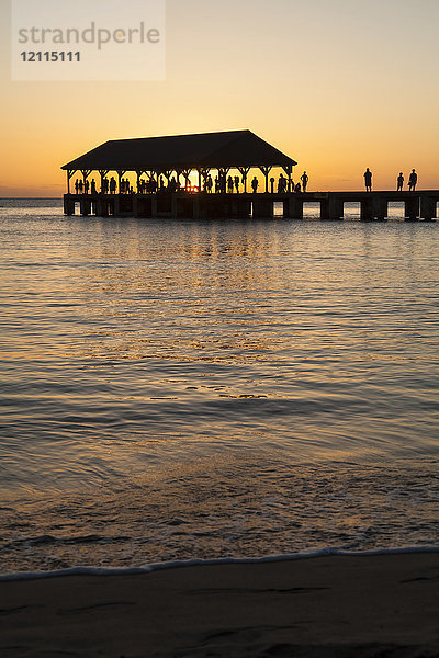 Sonnenuntergang über dem Meer und Silhouette von Touristen am Hanalei Pier  Hanalei Bay; Hanalei  Kauai  Hawaii  Vereinigte Staaten von Amerika