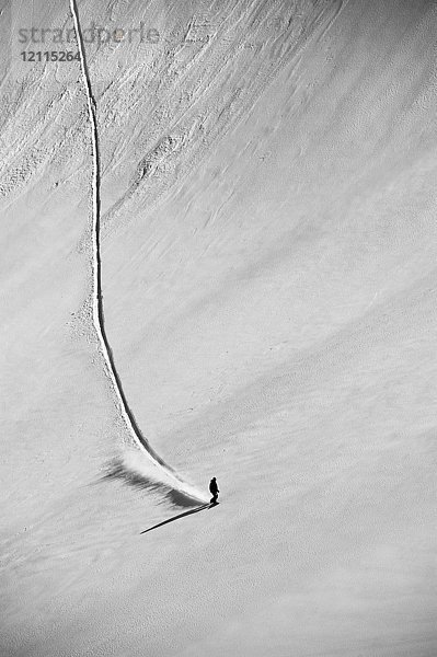 Ein professioneller Freeride-Snowboarder  der auf einer weitläufigen  verschneiten Piste neue Spuren zieht; British Columbia  Kanada