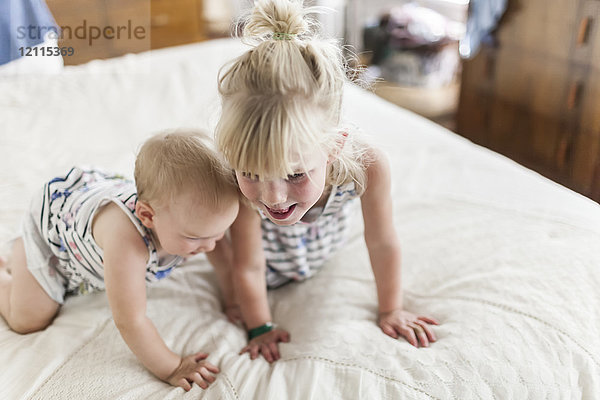 Zwei Schwestern  ein Baby und ein Kleinkind  spielen zusammen auf einem Bett; Sorrento  British Columbia  Kanada