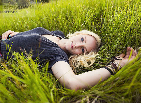 Porträt einer jungen Frau mit langen blonden Haaren  die in einem Park im Gras liegt; Edmonton  Alberta  Kanada