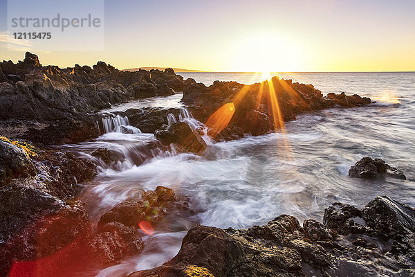 Dramatischer Sonnenuntergang über dem Meer mit Wasserfällen entlang der zerklüfteten Küstenlinie; Wailea  Maui  Hawaii  Vereinigte Staaten von Amerika