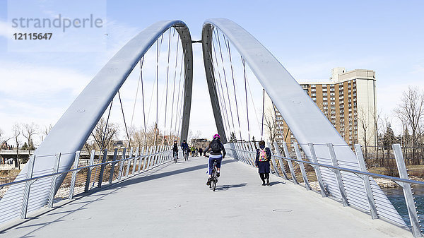 Fußgänger und Radfahrer beim Überqueren einer Brücke über den Bow River; Calgary  Alberta  Kanada