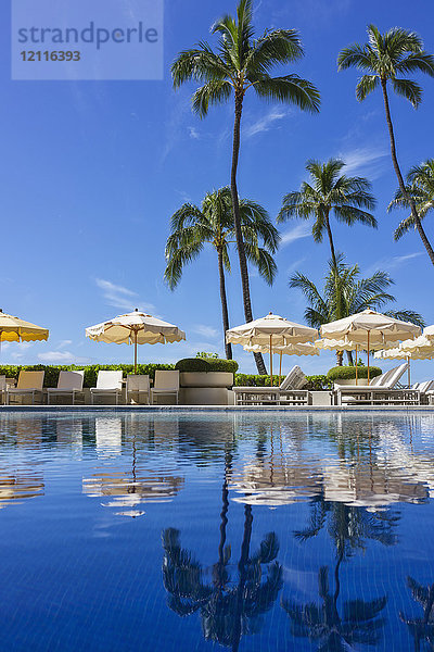 Halekalani Pool in Waikiki mit Palmen und Sonnenschirmen  die sich im Wasser spiegeln; Honolulu  Oahu  Hawaii  Vereinigte Staaten von Amerika