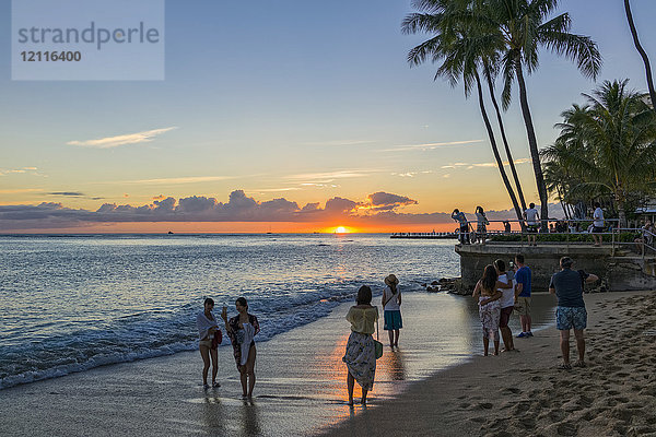 Touristen beobachten und fotografieren den Sonnenuntergang am Waikiki Beach; Honolulu  Oahu  Hawaii  Vereinigte Staaten von Amerika