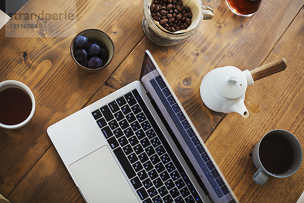 Hochwinkelansicht eines Laptop-Computers  einer Kaffeekanne und einer Kaffeetasse  die auf einem Tisch stehen.