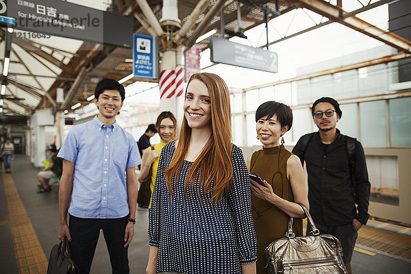 Kleine Gruppe von Menschen  die auf dem Bahnsteig einer U-Bahn-Station stehen  Tokio-Pendler.