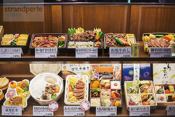 Hochwinkelansicht einer Auswahl von Bento-Schachteln mit traditionellen japanischen Lebensmitteln in den Regalen.