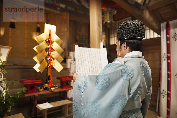 Rückansicht eines Priesters mit einer Schriftrolle im Shinto-Sakurai-Schrein  Fukuoka  Japan.