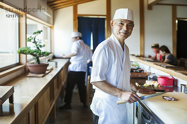 Zwei Köche arbeiten an einer Theke in einem japanischen Sushi-Restaurant.