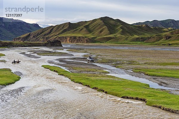 Zwei Reiter und ein vierrädriges Auto überqueren einen Fluss  Kurumduk-Tal  Provinz Naryn  Kirgisistan  Asien