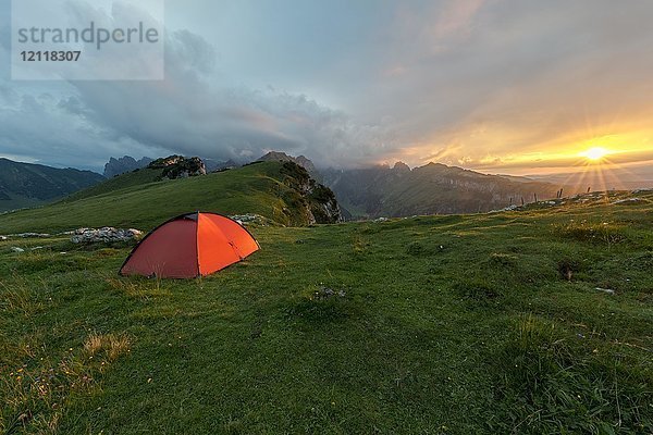 Dramatischer Sonnenuntergang mit Zelt vor bewölktem Himmel in den Bergen auf dem Alpsigel in Alpstein  Brülisau  Appenzell Innerrhoden  Schweiz  Europa