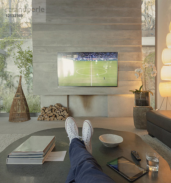 Persönliche Perspektive Frau schaut Fußball im Fernsehen im Wohnzimmer