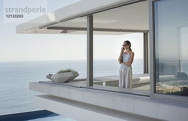 Frau  die auf einer modernen  luxuriösen Wohnung mit Blick auf das Meer telefoniert