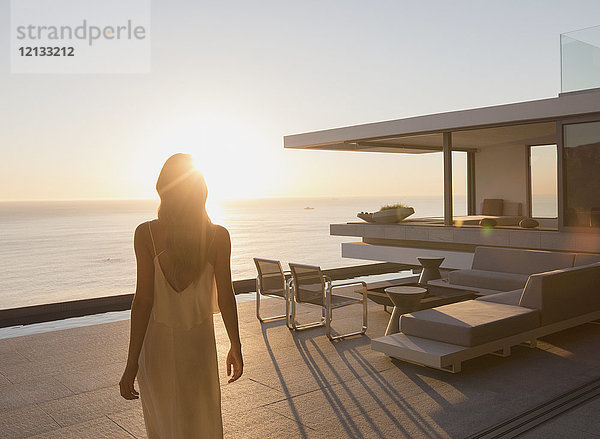 Frau zu Fuß auf ruhigen Sonnenuntergang modernen  luxuriösen Haus Schaufenster außen Terrasse mit Meerblick