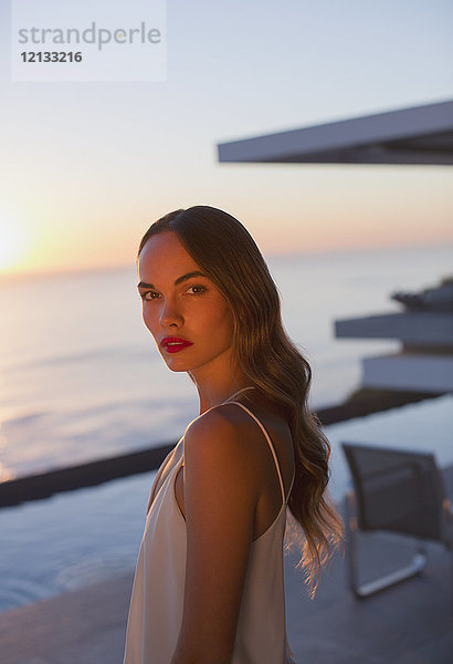 Porträt ernst  schöne Frau auf Sonnenuntergang Terrasse mit Meerblick
