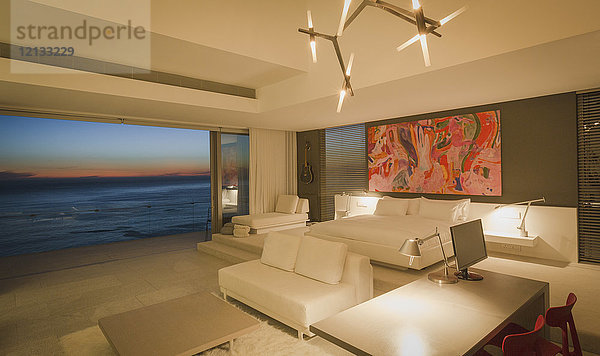 Beleuchtetes modernes  luxuriöses Schlafzimmer mit Meerblick in der Abenddämmerung