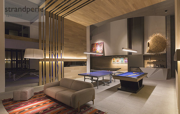 Beleuchteter Billardtisch und Tischtennisplatte in einem modernen  luxuriösen Haus  das als Spielzimmer dient