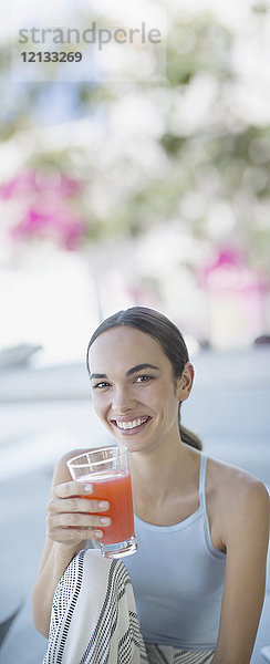 Porträt einer lächelnden  selbstbewussten brünetten Frau  die Saft trinkt