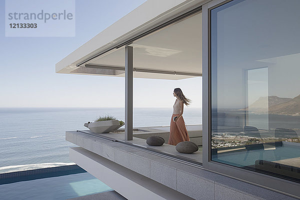 Frau mit Blick auf das Meer auf modernen  luxuriösen Haus Schaufenster außen Balkon