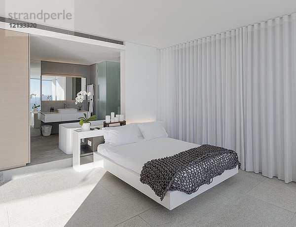 Bett in modernem  luxuriösem Musterschlafzimmer mit eigenem Bad
