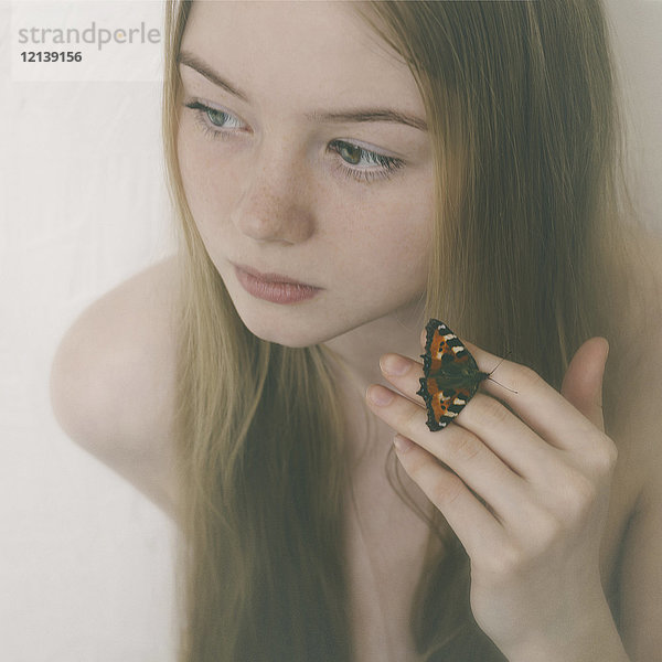 Schmetterling auf den Fingern eines kaukasischen Teenagers