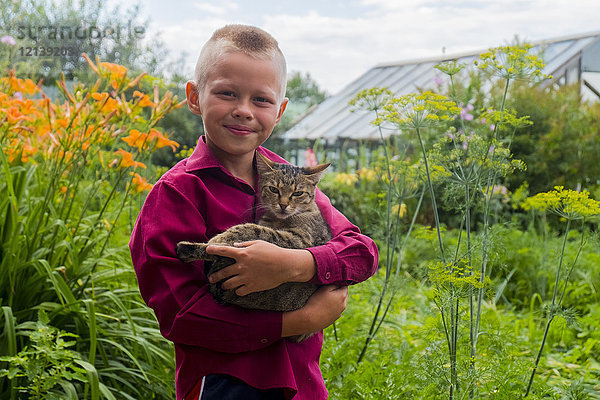 Kaukasischer Junge hält Katze auf Bauernhof