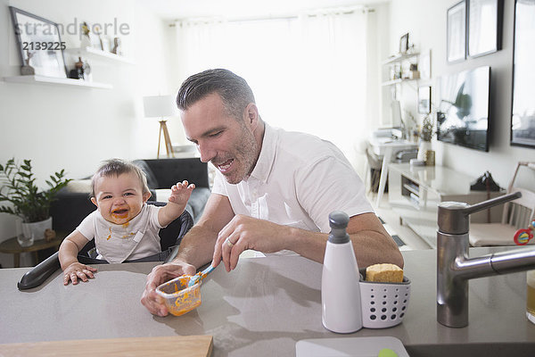 Vater füttert glückliches Baby Sohn