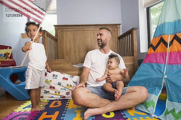 Vater beobachtet Sohn beim Schwenken der amerikanischen Flagge im Spielzimmer