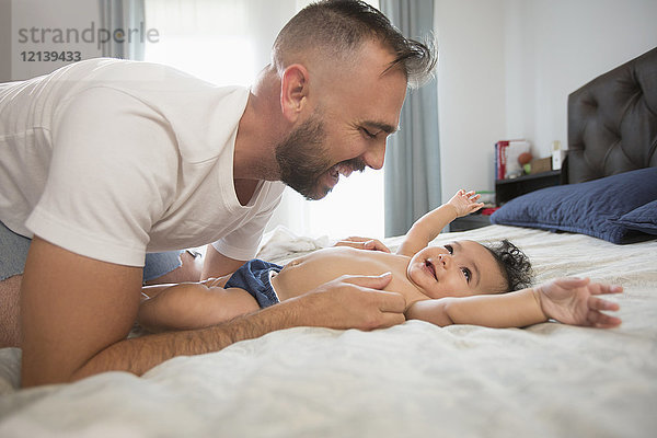 Vater liegt auf dem Bett und spielt mit seiner kleinen Tochter